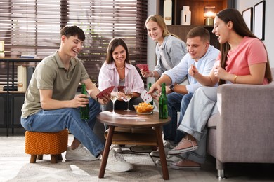 Photo of Group of friends playing cards at wooden table indoors