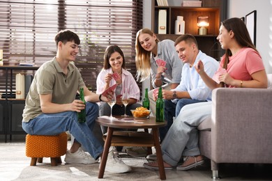 Photo of Group of friends playing cards at wooden table indoors