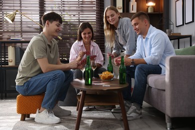Photo of Group of friends playing cards at wooden table indoors