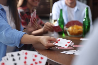 Photo of Friends playing cards at wooden table indoors, selective focus