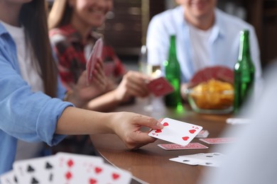 Photo of Friends playing cards at wooden table indoors, selective focus