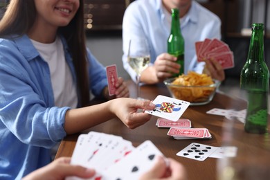 Photo of Friends playing cards at wooden table indoors, closeup