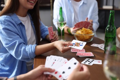 Photo of Friends playing cards at wooden table indoors, closeup