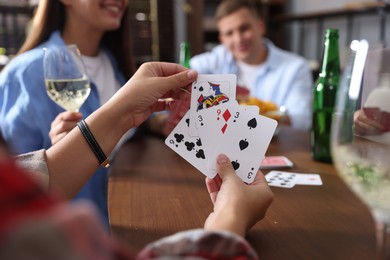 Photo of Friends playing cards at wooden table indoors, selective focus