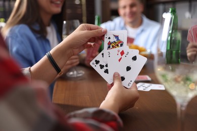 Photo of Friends playing cards at wooden table indoors, selective focus