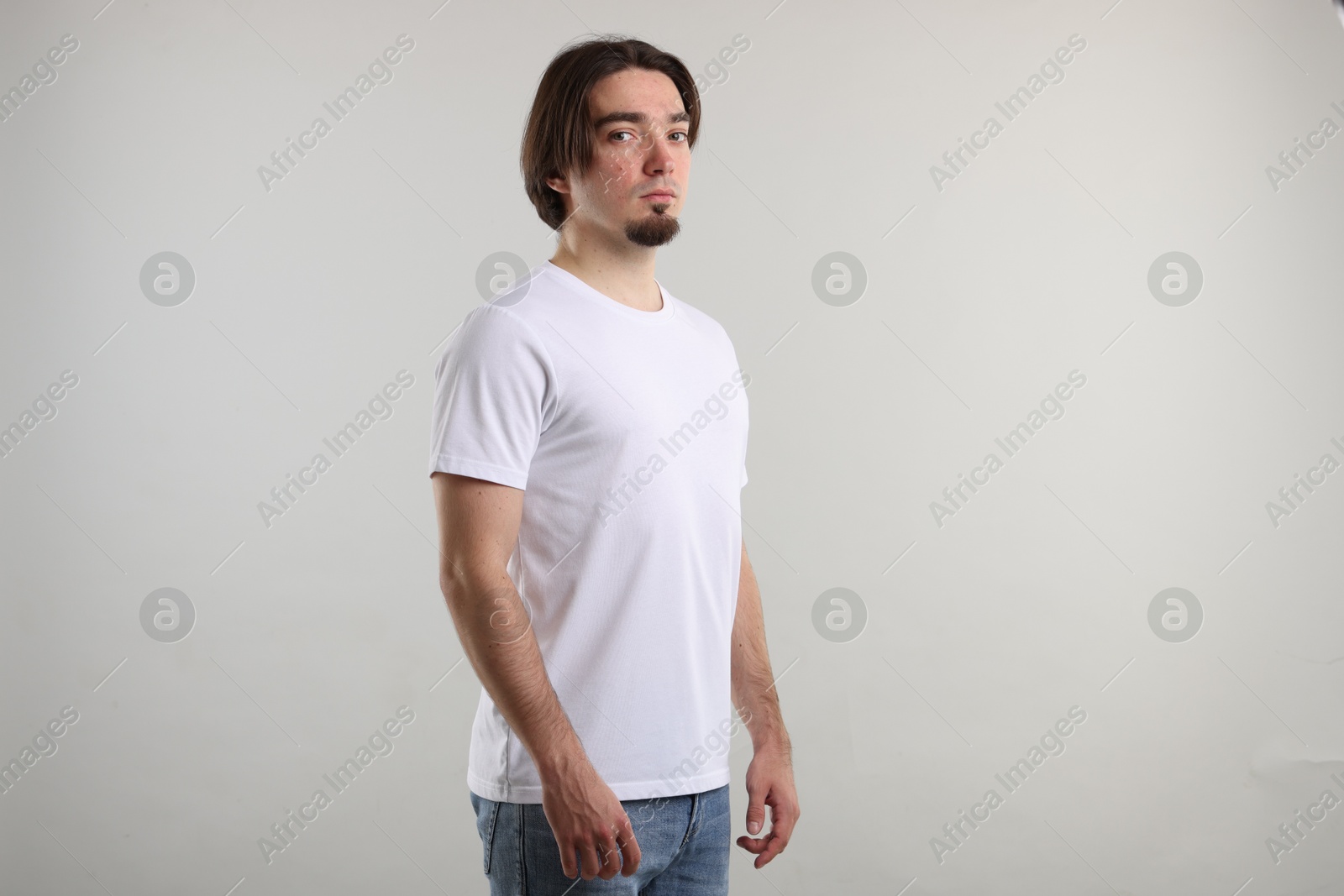 Photo of Young man wearing stylish white t-shirt near light grey background. Mockup for design