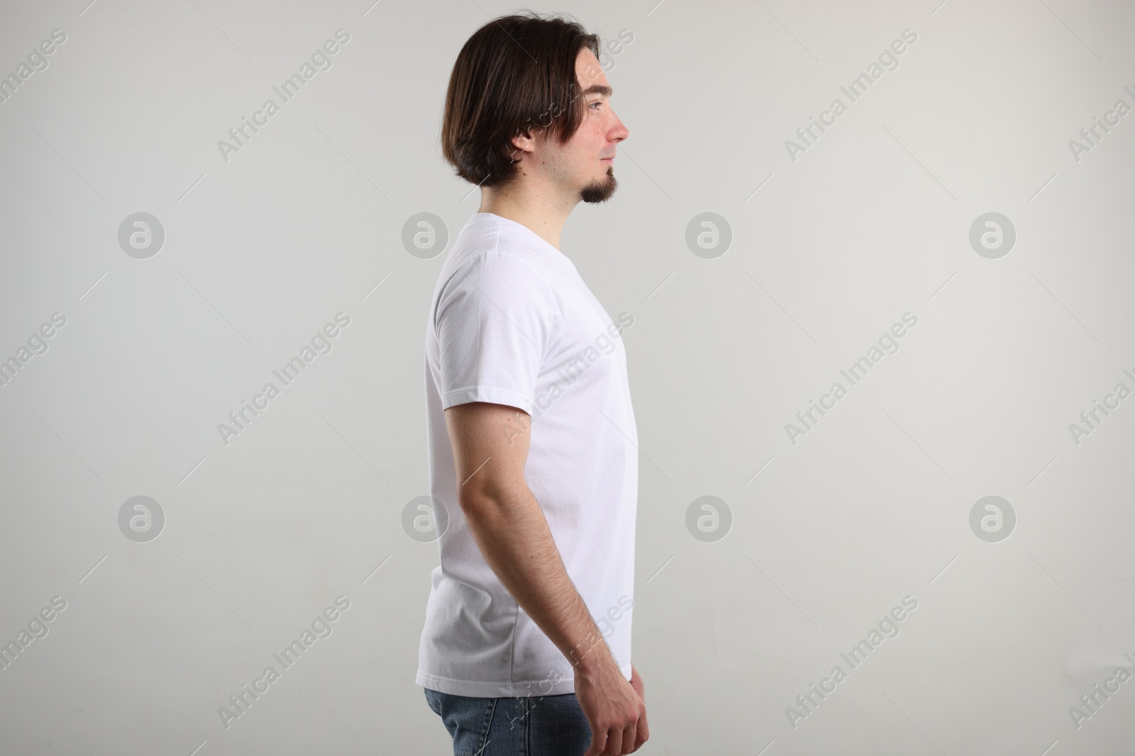 Photo of Young man wearing stylish white t-shirt near light grey background. Mockup for design