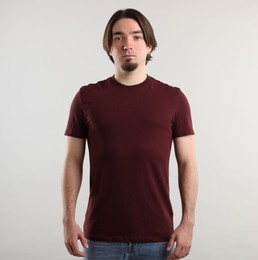 Photo of Young man wearing stylish brown t-shirt near light grey background. Mockup for design