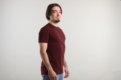 Photo of Young man wearing stylish brown t-shirt near light grey background. Mockup for design