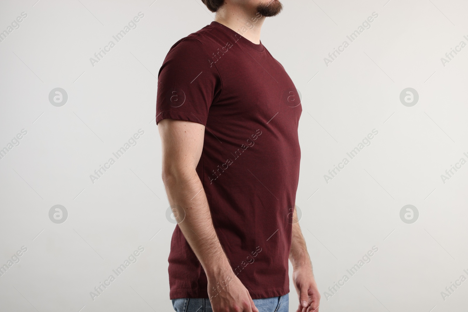 Photo of Young man wearing stylish brown t-shirt near light grey background, closeup. Mockup for design