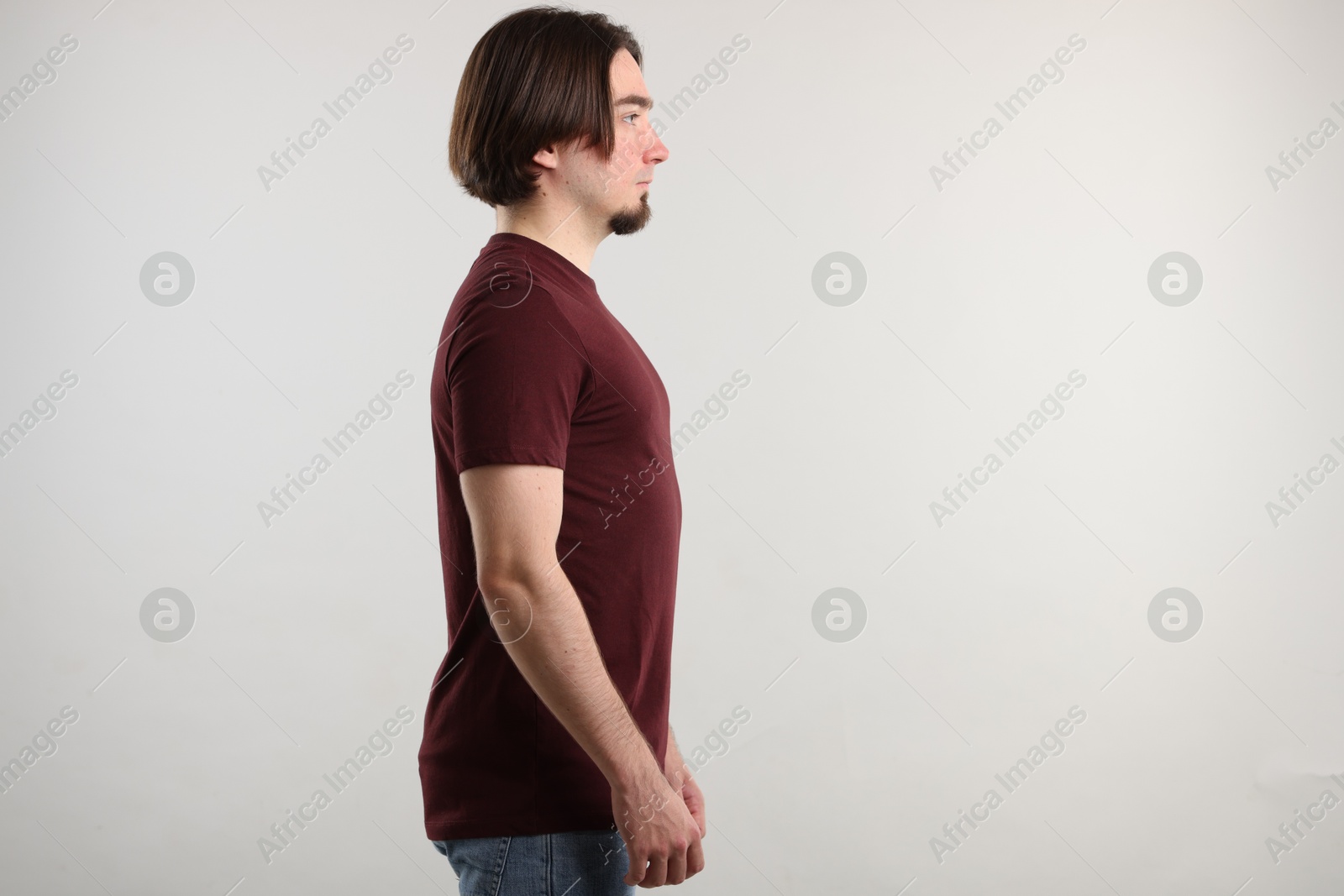 Photo of Young man wearing stylish brown t-shirt near light grey background. Mockup for design