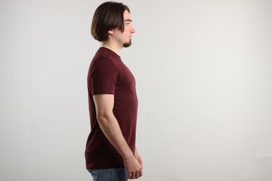 Photo of Young man wearing stylish brown t-shirt near light grey background. Mockup for design