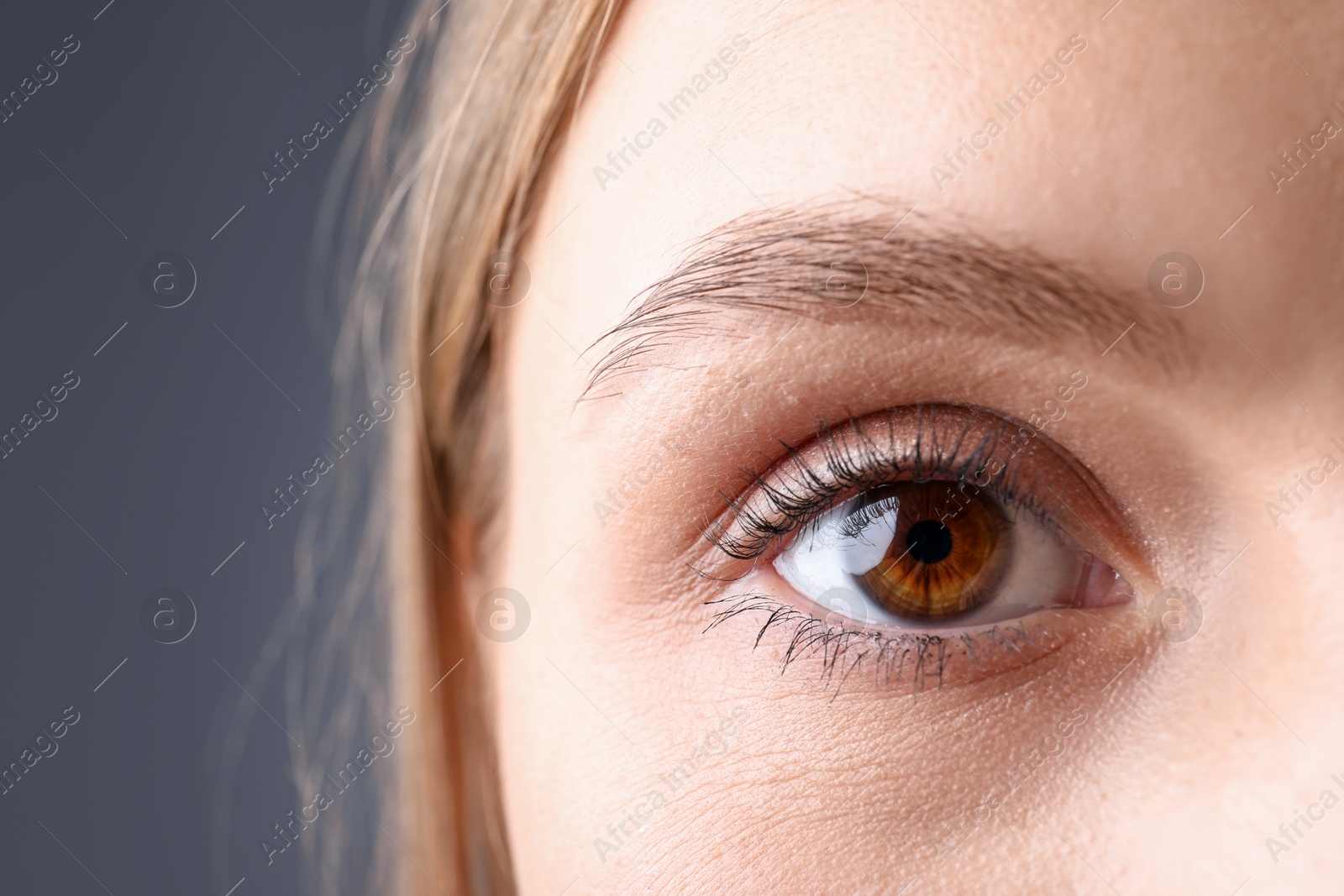 Photo of Woman with beautiful eyes on grey background, closeup. Space for text