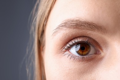Photo of Woman with beautiful eyes on grey background, closeup. Space for text