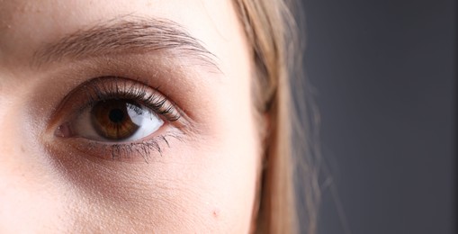 Photo of Woman with beautiful eyes on grey background, closeup. Space for text