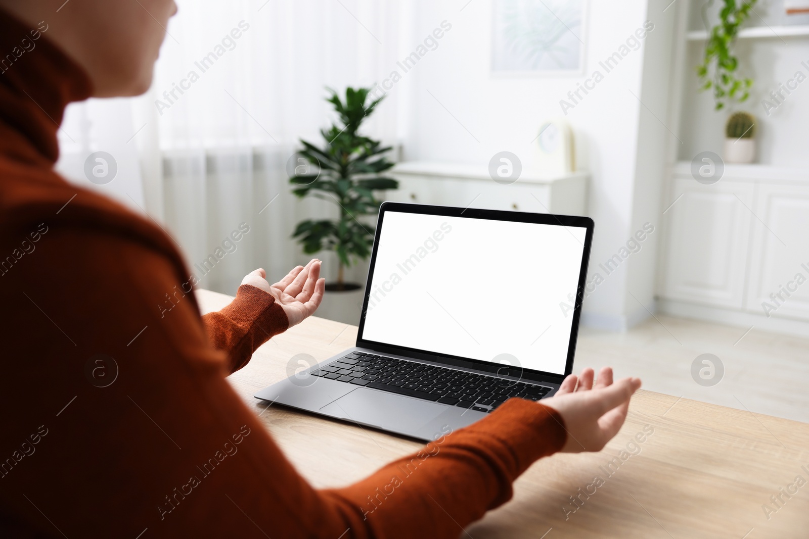 Photo of Woman working with laptop at wooden table indoors, closeup. Mockup for design