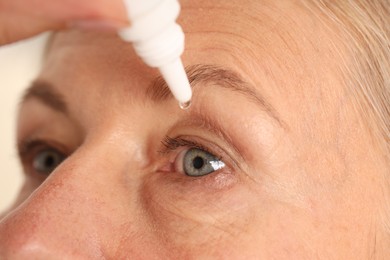 Photo of Woman applying eye drops on light background, closeup