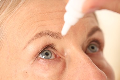 Photo of Woman applying eye drops on light background, closeup
