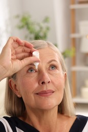 Photo of Senior woman applying eye drops at home