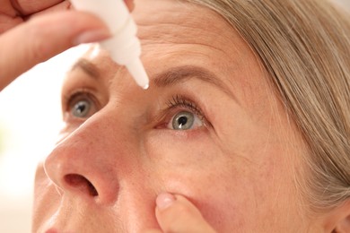 Photo of Woman applying eye drops on light background, closeup