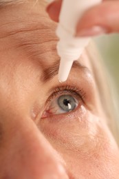 Photo of Woman applying eye drops on blurred background, closeup