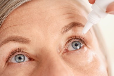 Photo of Woman applying eye drops on blurred background, closeup