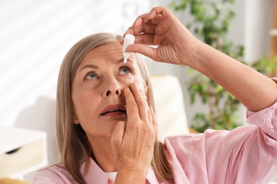 Photo of Senior woman applying eye drops at home