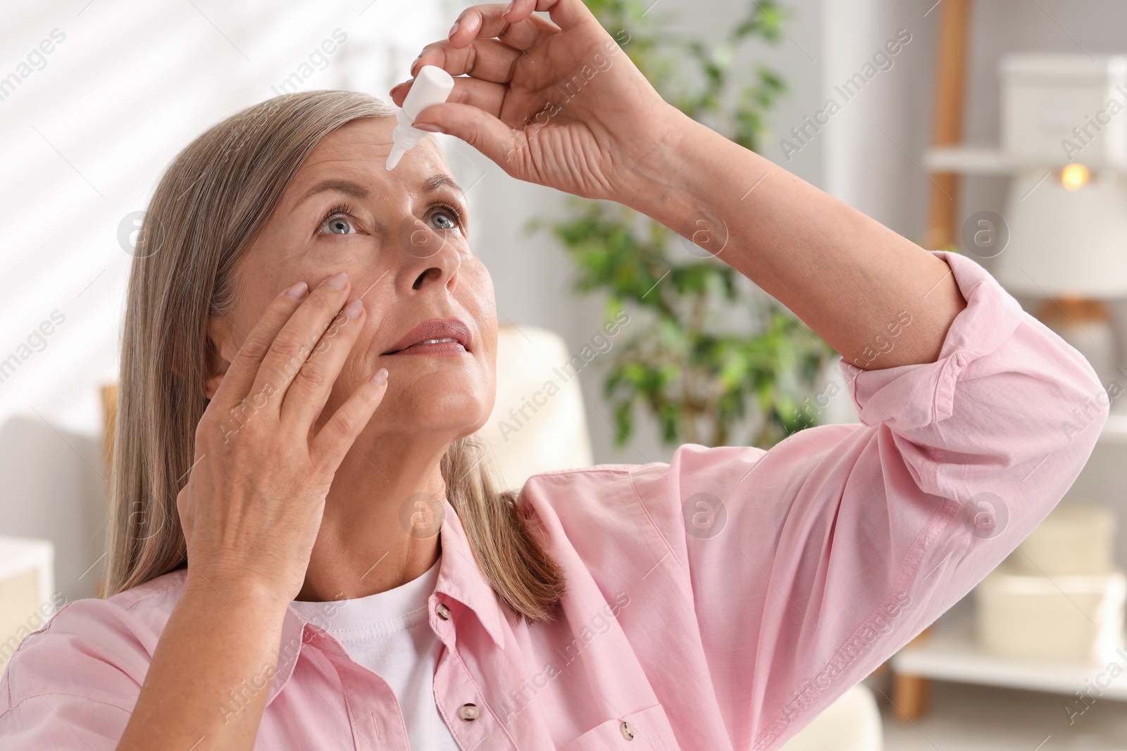 Photo of Senior woman applying eye drops at home