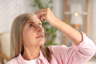 Photo of Senior woman applying eye drops at home