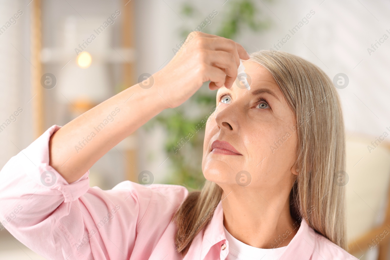 Photo of Senior woman applying eye drops at home