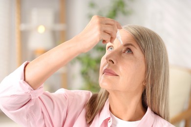 Photo of Senior woman applying eye drops at home