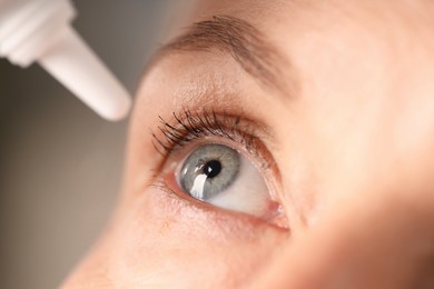 Photo of Woman applying eye drops on blurred background, closeup
