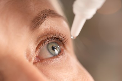 Photo of Woman applying eye drops on blurred background, closeup