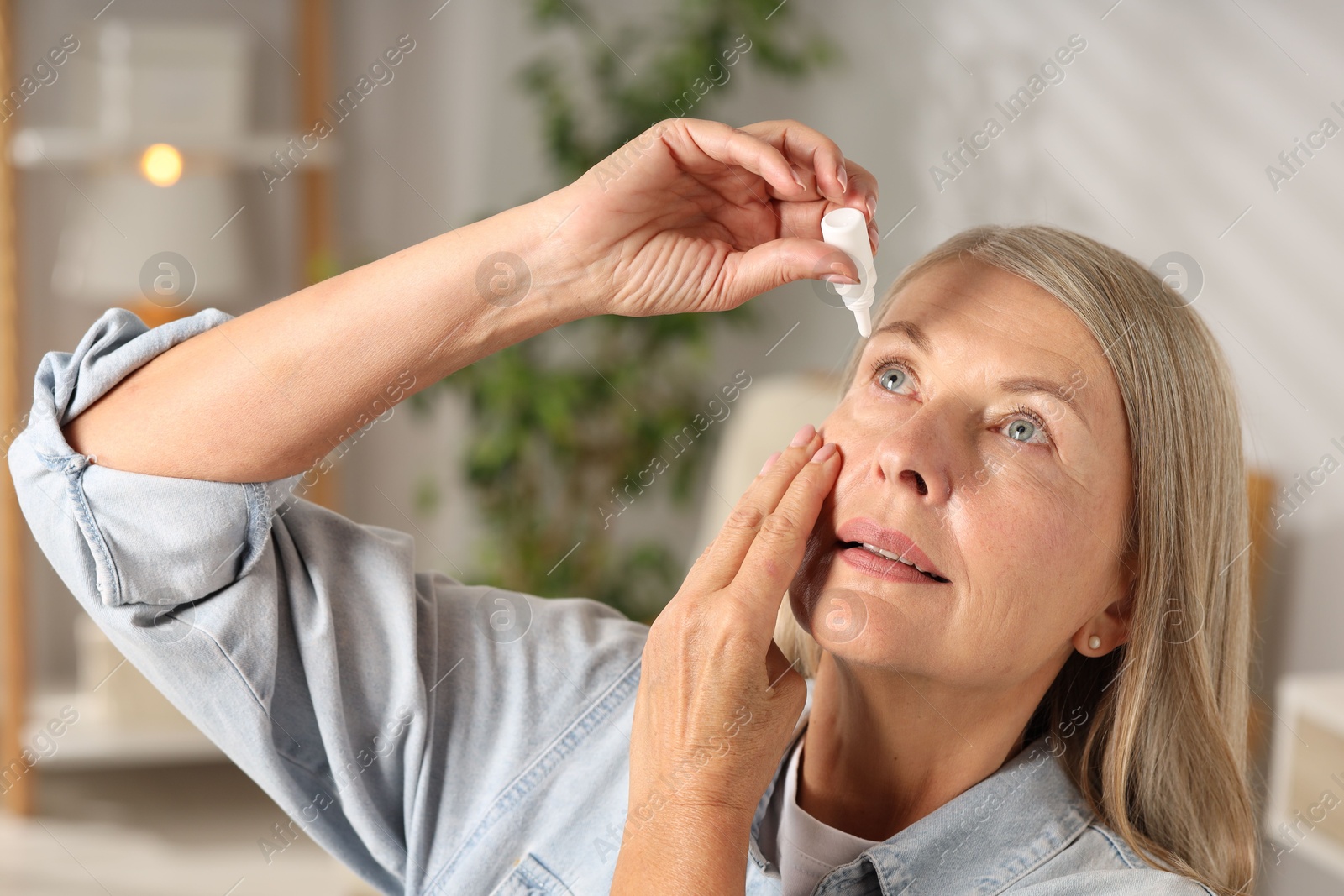 Photo of Senior woman applying eye drops at home