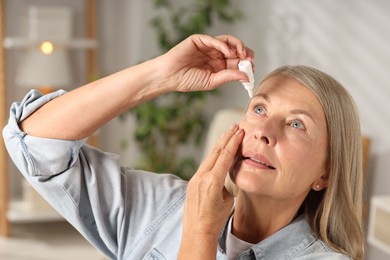 Photo of Senior woman applying eye drops at home