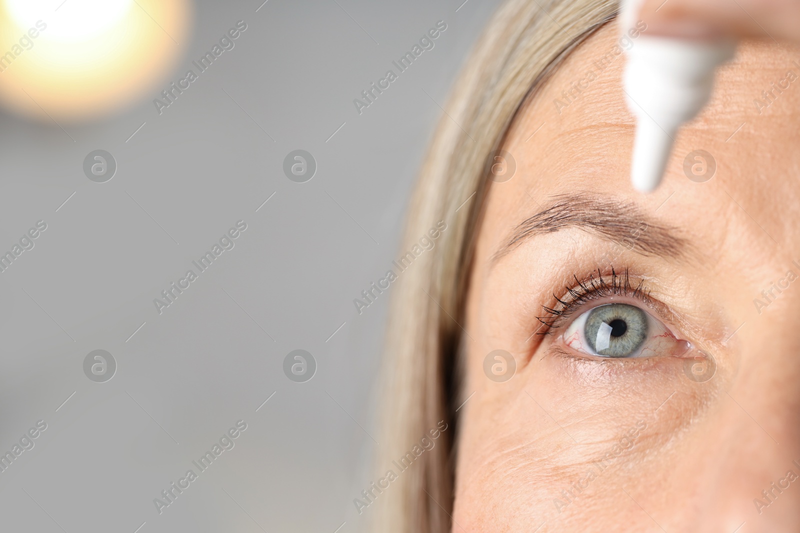 Photo of Woman applying eye drops on light background, closeup. Space for text