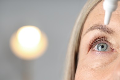 Photo of Woman applying eye drops on blurred background, closeup. Space for text