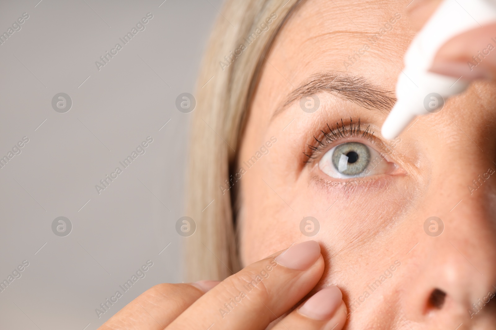Photo of Woman applying eye drops on light background, closeup. Space for text