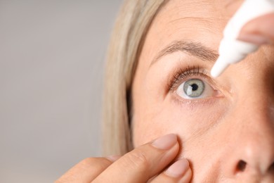 Photo of Woman applying eye drops on light background, closeup. Space for text