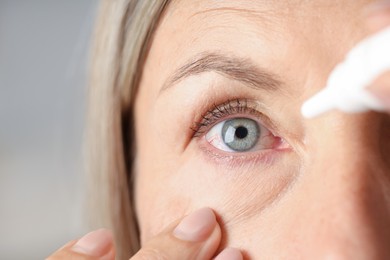 Photo of Woman applying eye drops on light background, closeup