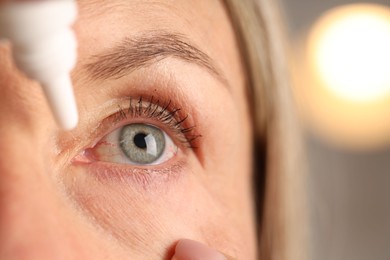 Photo of Woman applying eye drops on blurred background, closeup