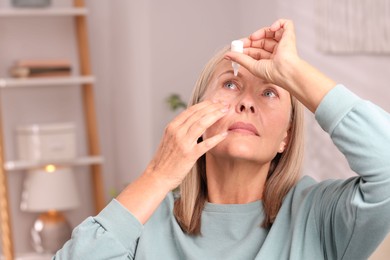 Photo of Senior woman applying eye drops at home. Space for text