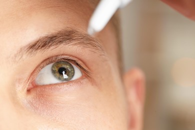 Photo of Man applying eye drops on blurred background, closeup