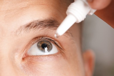Photo of Man applying eye drops on blurred background, closeup