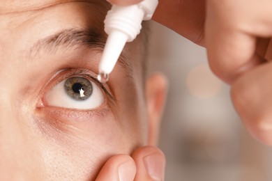 Photo of Man applying eye drops on blurred background, closeup