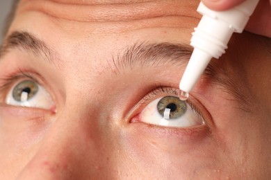 Photo of Young man applying eye drops, closeup view