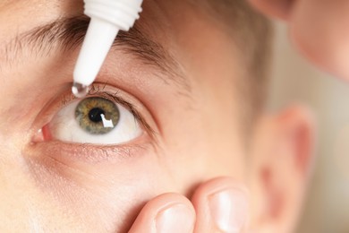 Photo of Man applying eye drops on blurred background, closeup