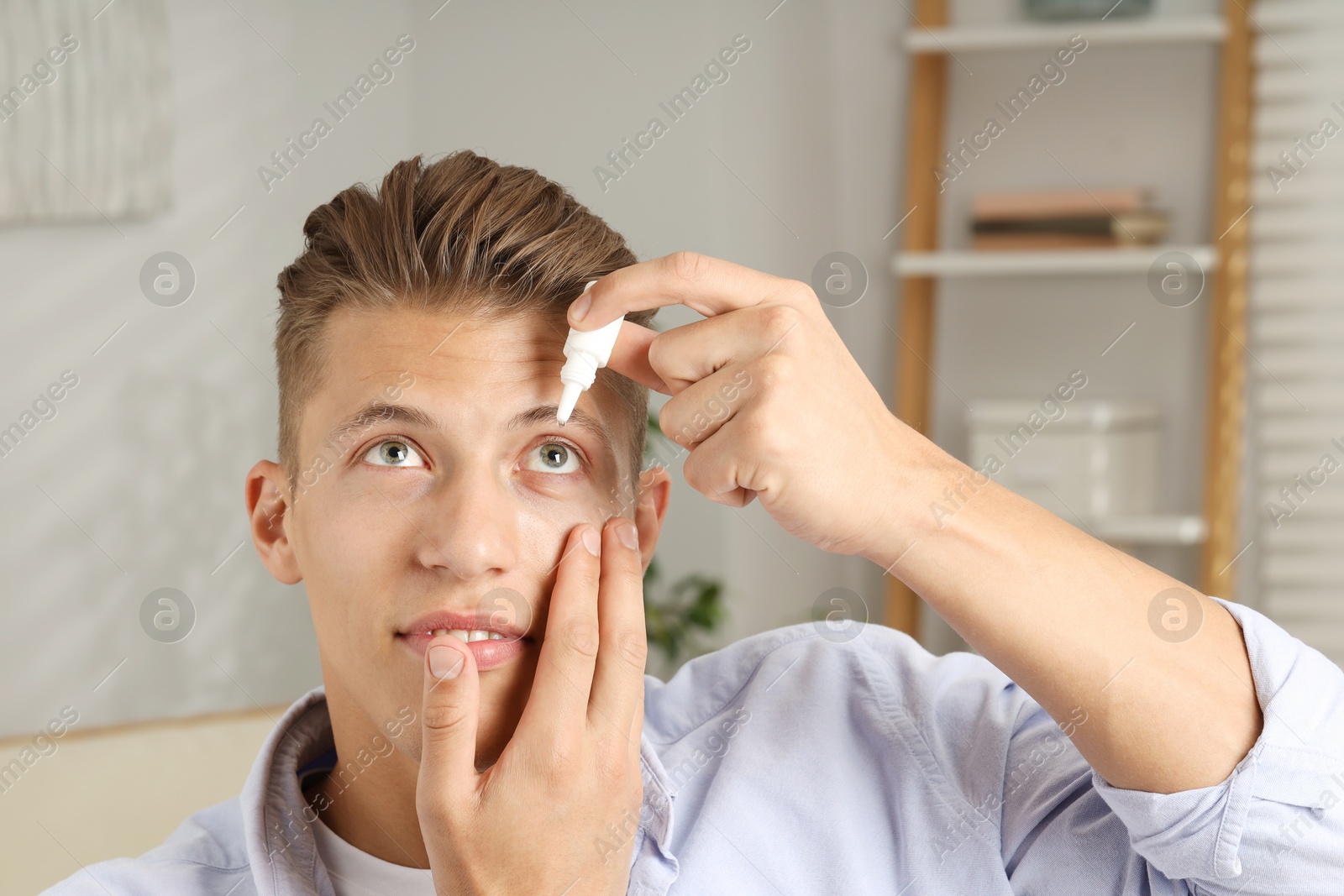 Photo of Young man applying eye drops at home