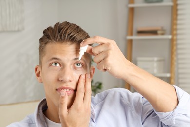 Photo of Young man applying eye drops at home
