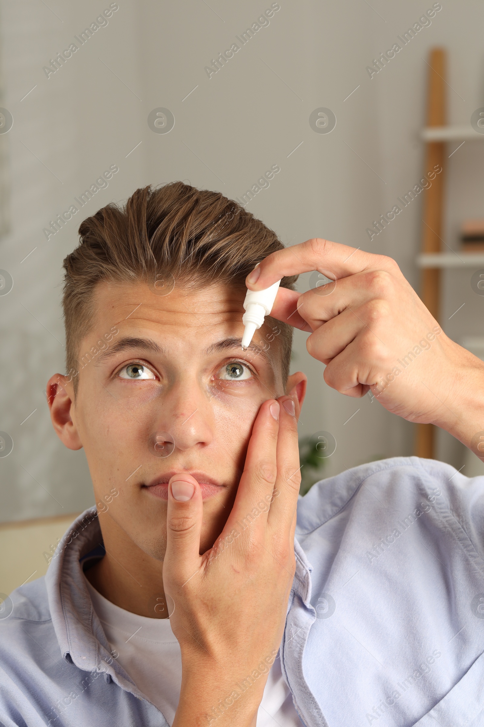 Photo of Young man applying eye drops at home